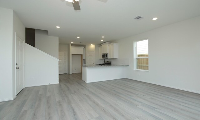 unfurnished living room featuring light wood-style flooring, a ceiling fan, visible vents, recessed lighting, and baseboards