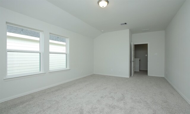 empty room featuring light carpet, baseboards, vaulted ceiling, and visible vents