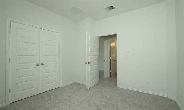 unfurnished bedroom with visible vents, baseboards, a closet, and light colored carpet