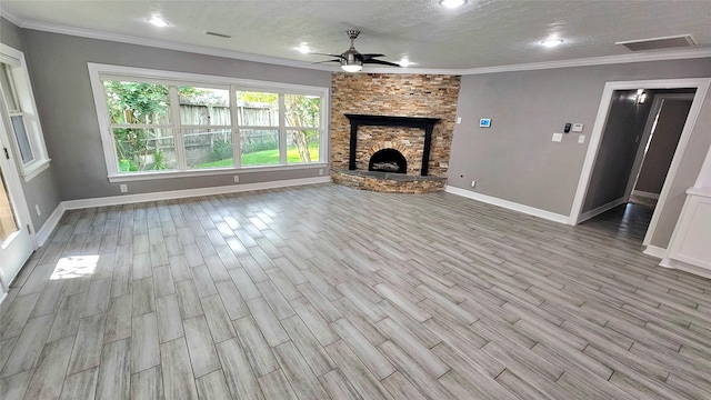 unfurnished living room with a stone fireplace, light hardwood / wood-style flooring, a textured ceiling, ornamental molding, and ceiling fan