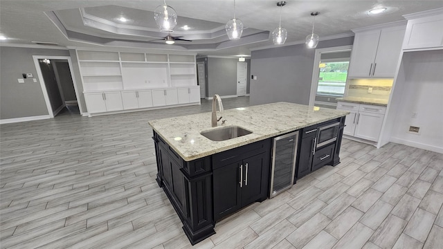 kitchen featuring pendant lighting, sink, white cabinetry, wine cooler, and a tray ceiling