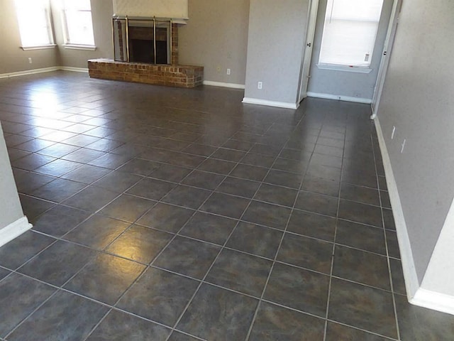 unfurnished living room featuring a fireplace and dark tile patterned flooring