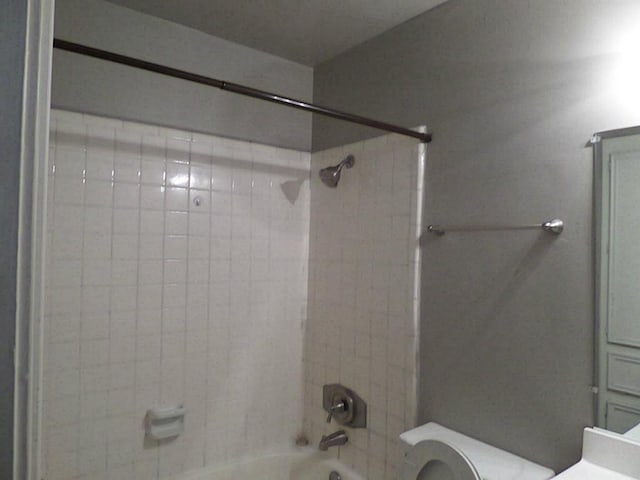 full bathroom with tiled shower / bath, vanity, and toilet