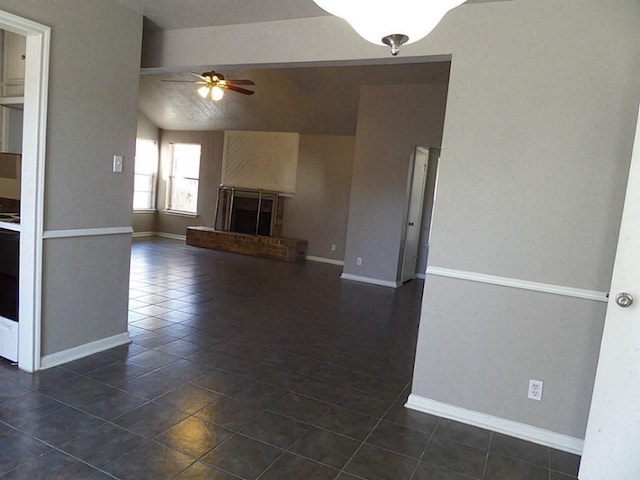 unfurnished living room featuring dark tile patterned floors, a brick fireplace, lofted ceiling, and ceiling fan