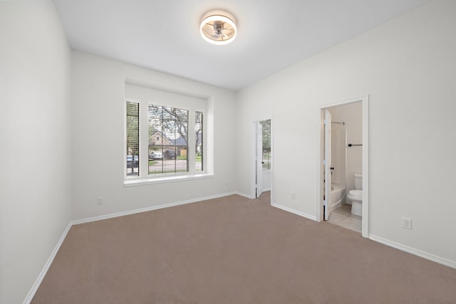 unfurnished bedroom with ensuite bath and light carpet