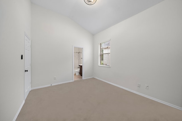 unfurnished bedroom with light colored carpet, vaulted ceiling, and ensuite bath