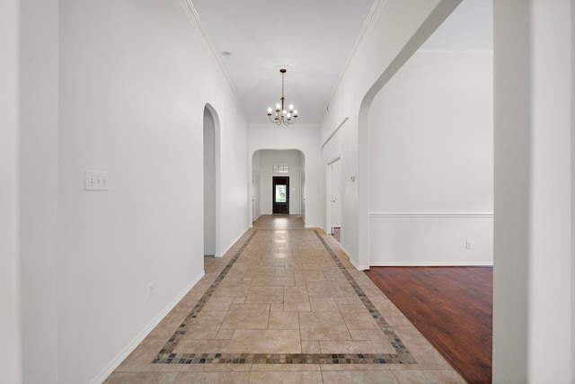 hall with ornamental molding and a chandelier