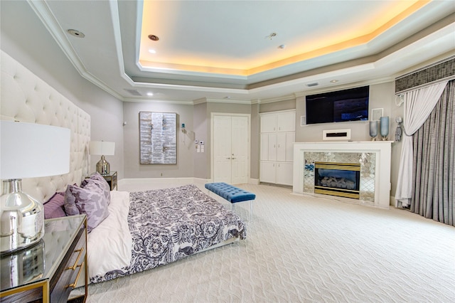 carpeted bedroom with ornamental molding, a fireplace, and a tray ceiling