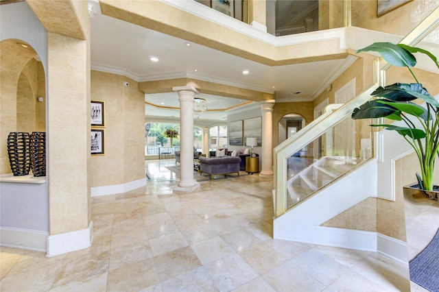 entrance foyer with crown molding, a towering ceiling, and decorative columns