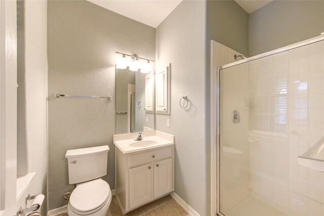 bathroom with a shower with door, vanity, tile patterned floors, and toilet