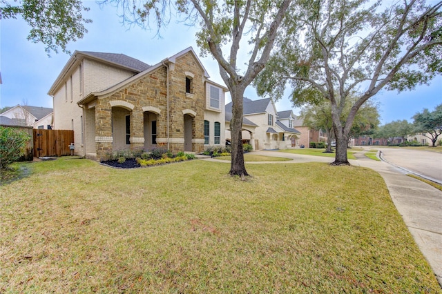 view of front of property with brick siding, stone siding, fence, and a front yard