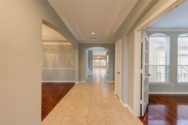 corridor featuring crown molding, plenty of natural light, and light wood-type flooring