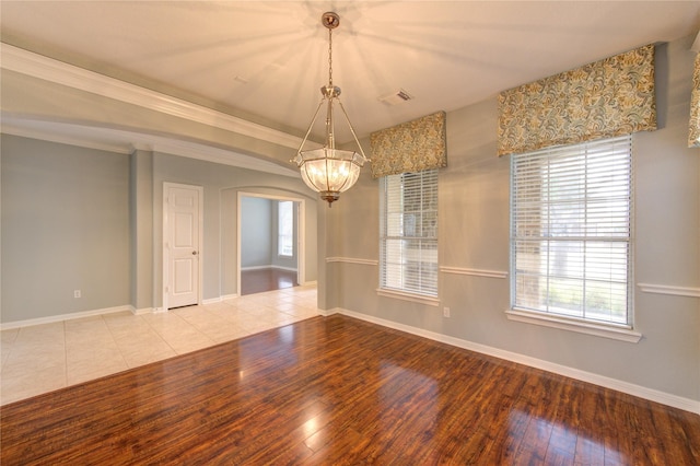 empty room featuring crown molding, a chandelier, and light wood-type flooring