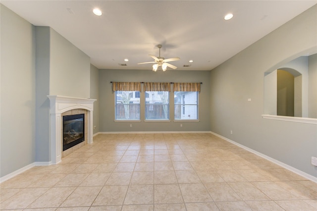 unfurnished living room featuring ceiling fan, a fireplace, and light tile patterned floors