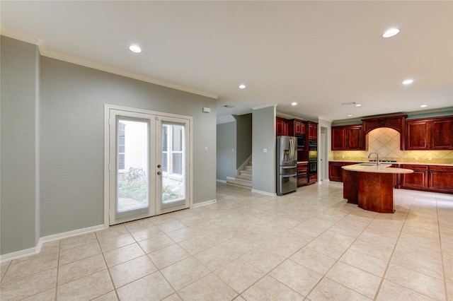 kitchen with french doors, tasteful backsplash, a center island with sink, ornamental molding, and stainless steel fridge