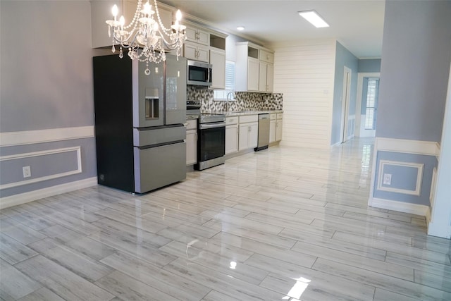 kitchen with appliances with stainless steel finishes, pendant lighting, tasteful backsplash, sink, and white cabinets