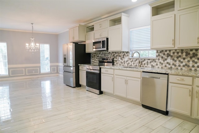 kitchen featuring pendant lighting, sink, crown molding, appliances with stainless steel finishes, and light stone countertops