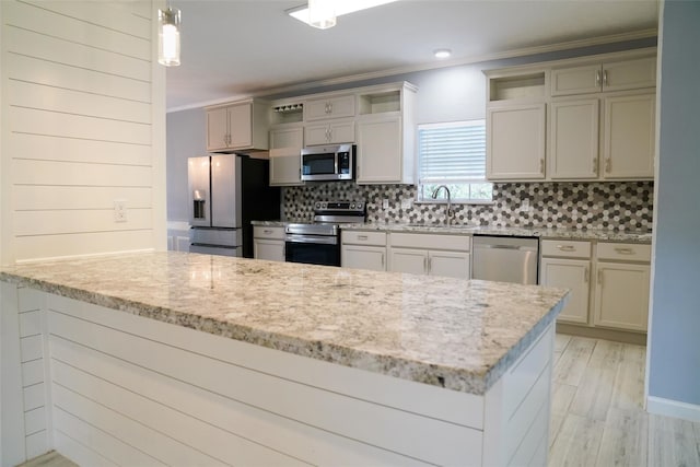 kitchen featuring appliances with stainless steel finishes, backsplash, light stone counters, decorative light fixtures, and kitchen peninsula