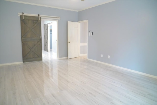 unfurnished room featuring crown molding, a barn door, and light hardwood / wood-style flooring