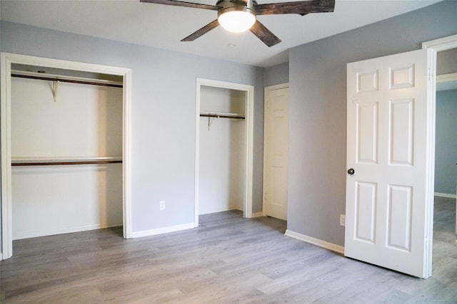 unfurnished bedroom with ceiling fan, two closets, and light wood-type flooring