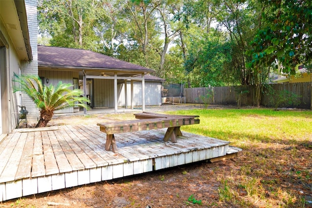 wooden deck featuring a trampoline and a lawn