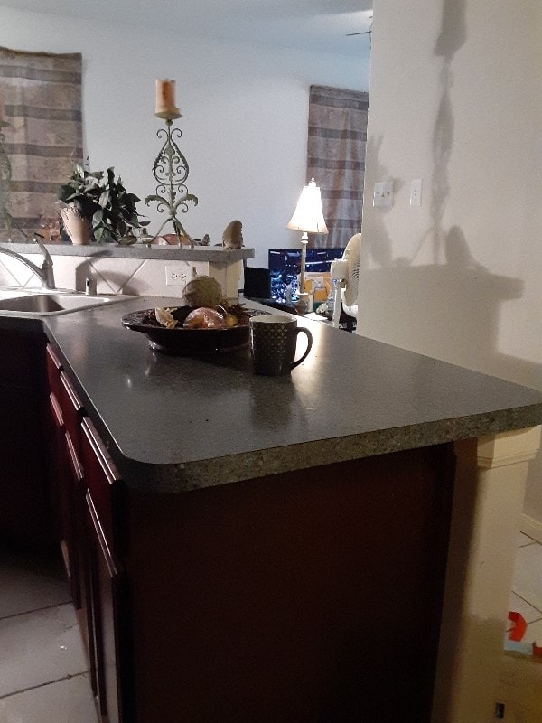 kitchen featuring dark brown cabinetry, sink, and light tile patterned floors