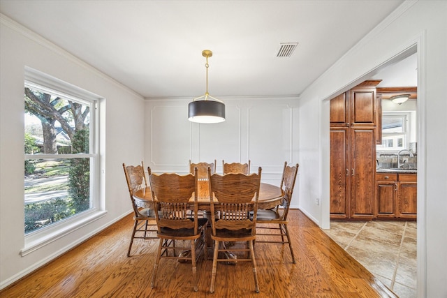 dining room featuring crown molding, sink, and light wood-type flooring