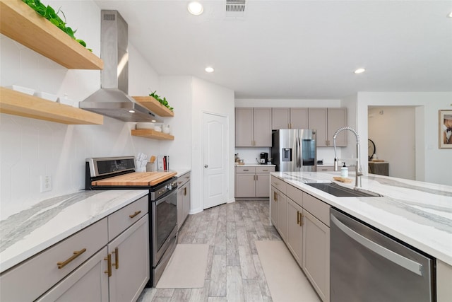 kitchen with appliances with stainless steel finishes, light stone countertops, sink, and island range hood