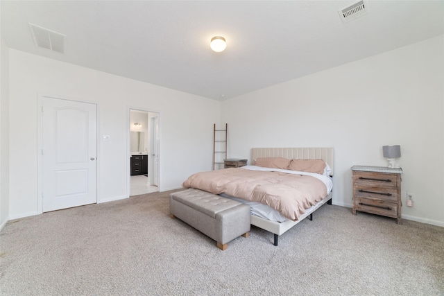 bedroom with ensuite bathroom and carpet flooring