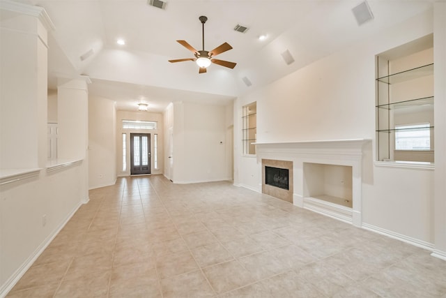 unfurnished living room featuring a fireplace, lofted ceiling, light tile patterned floors, ceiling fan, and built in shelves