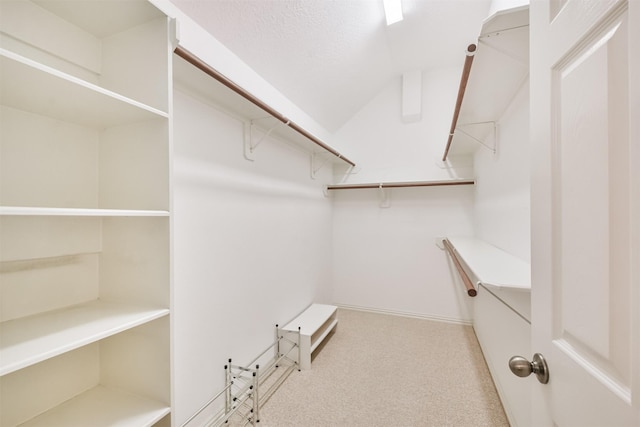 walk in closet featuring vaulted ceiling and light carpet