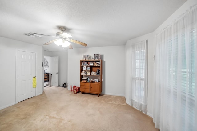 interior space with light carpet, ceiling fan, and a textured ceiling