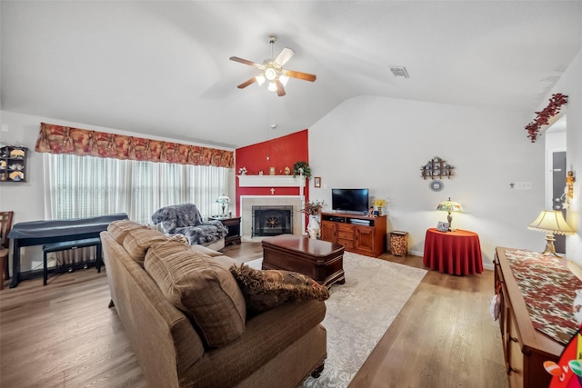 living room featuring ceiling fan, lofted ceiling, hardwood / wood-style floors, and a tile fireplace