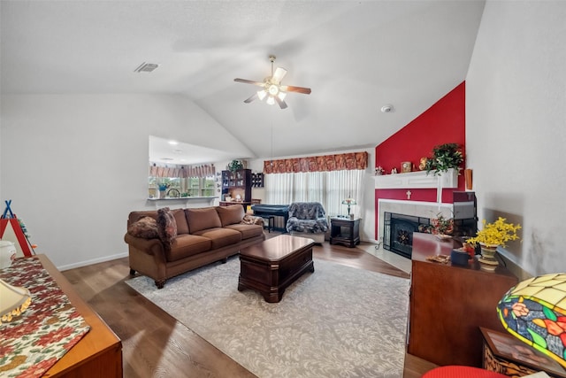 living room featuring wood-type flooring, a tile fireplace, ceiling fan, and vaulted ceiling