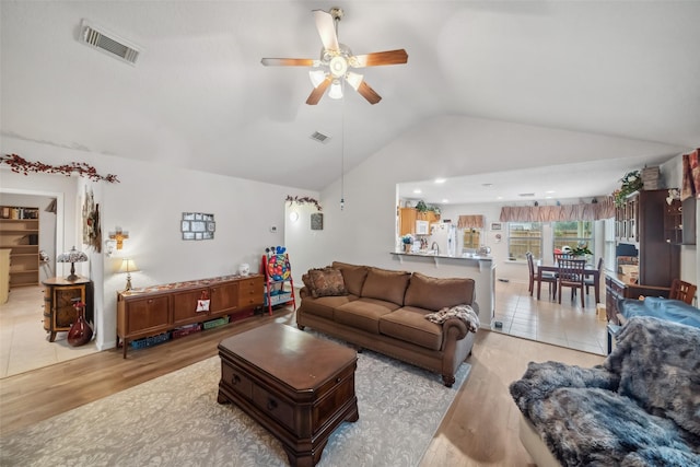 living room featuring vaulted ceiling, ceiling fan, and light hardwood / wood-style flooring