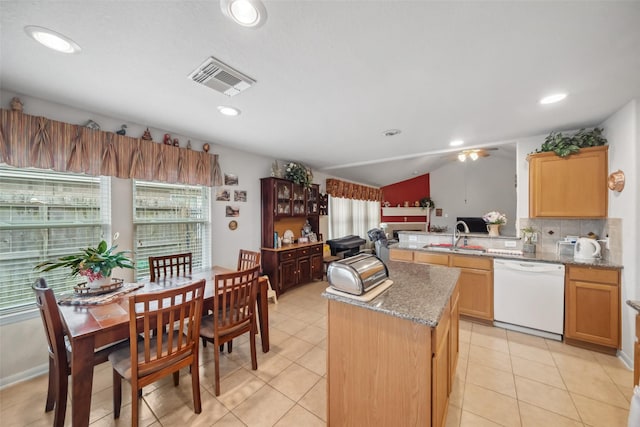 kitchen featuring dishwasher, sink, a center island, light stone countertops, and a healthy amount of sunlight