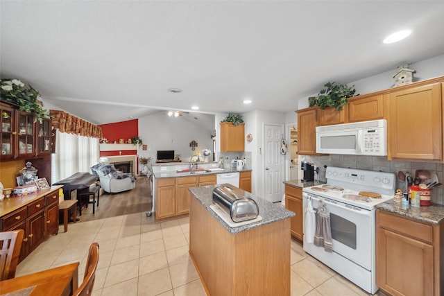 kitchen featuring light tile patterned floors, white appliances, sink, tasteful backsplash, and a kitchen island