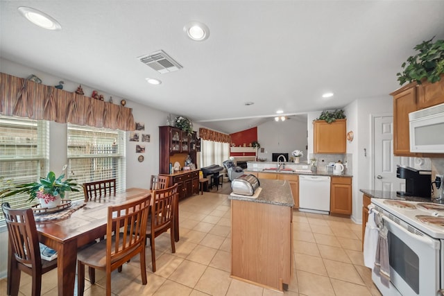 kitchen featuring white appliances, light tile patterned floors, a kitchen island, and a wealth of natural light