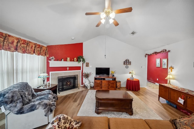 living room featuring ceiling fan, a fireplace, vaulted ceiling, and light hardwood / wood-style flooring