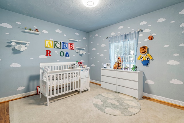 carpeted bedroom with a nursery area and a textured ceiling