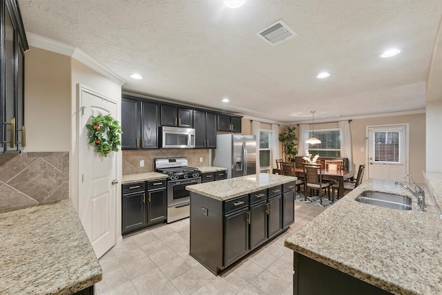 kitchen featuring a kitchen island, appliances with stainless steel finishes, decorative light fixtures, sink, and light stone countertops