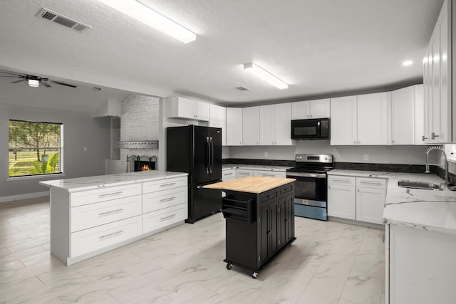 kitchen with sink, white cabinets, a center island, black appliances, and light stone countertops