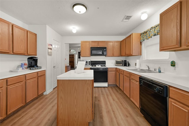 kitchen with a kitchen island, sink, light hardwood / wood-style floors, black appliances, and a textured ceiling