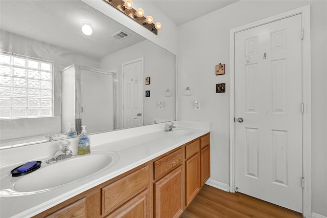 bathroom featuring walk in shower, vanity, and wood-type flooring