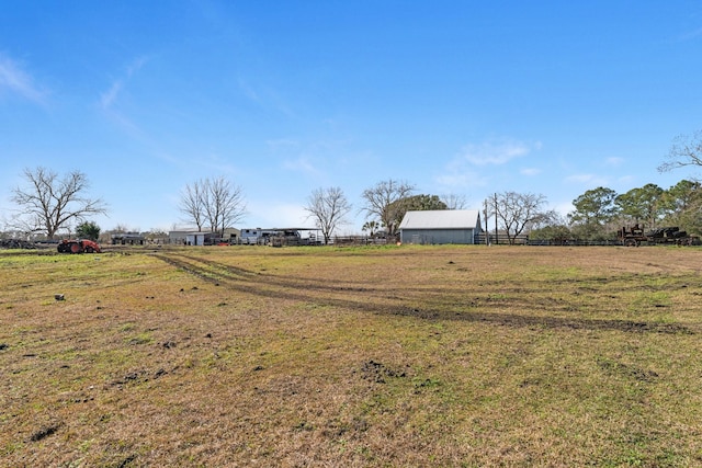 view of yard featuring an outbuilding, a rural view, and fence