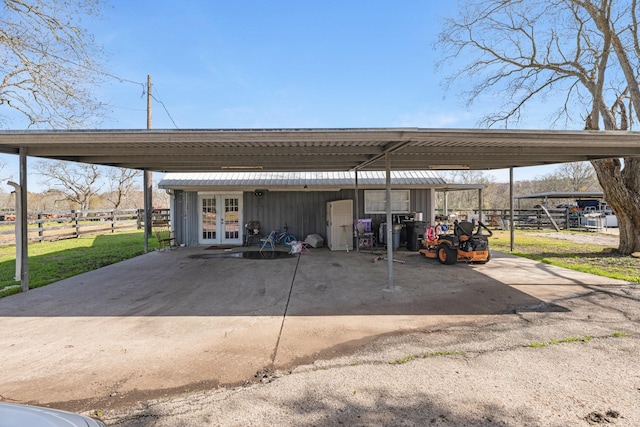 view of car parking featuring french doors, fence, and a detached carport