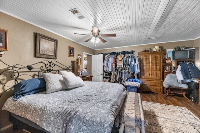 bedroom featuring ceiling fan, wood finished floors, visible vents, a closet, and crown molding