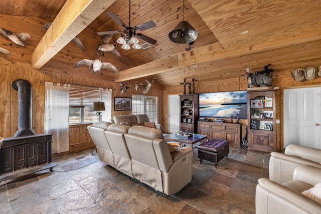 living room featuring stone tile floors, wood ceiling, a wood stove, ceiling fan, and wooden walls