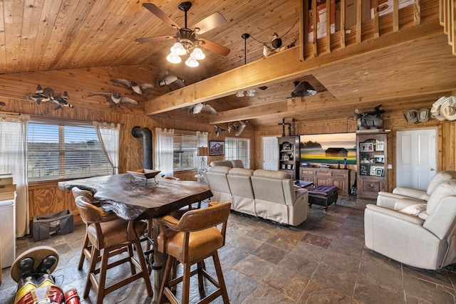 dining area featuring a wood stove, wooden ceiling, wood walls, and stone tile floors