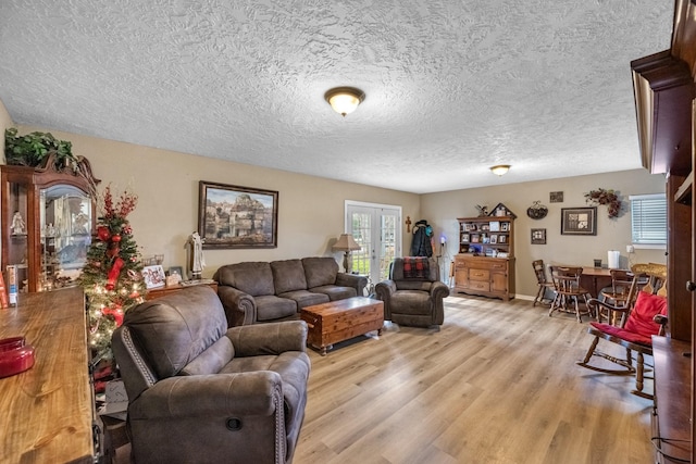 living area featuring french doors, a textured ceiling, and light wood finished floors